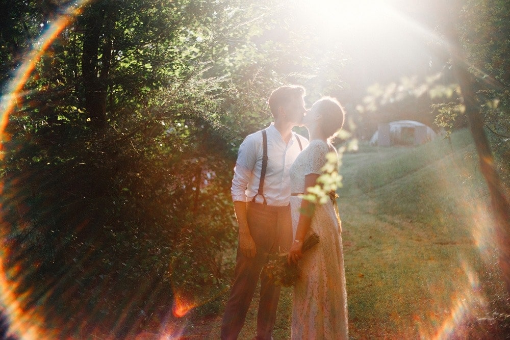 married couple at sunset in rainbow lens flare