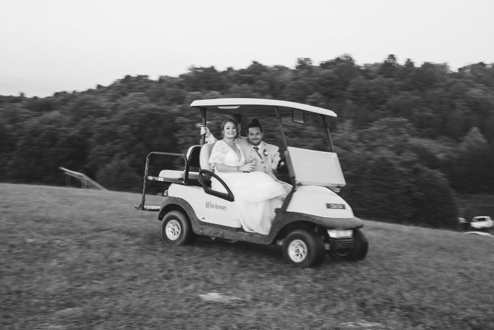 bride and groom riding away in golf cart
